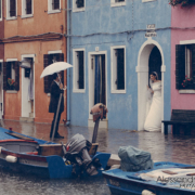 la coppia di sposi si ripara dalla pioggia sotto un portego a Burano