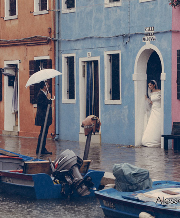 la coppia di sposi si ripara dalla pioggia sotto un portego a Burano